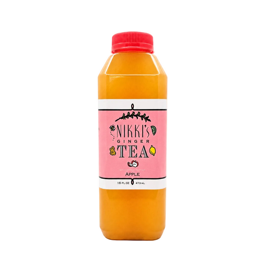 A bottle of Nikki's Ginger Tea Apple flavor, filled with orange tea and featuring a pink label with a red cap, set against a plain white background.