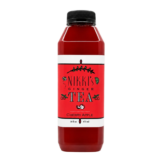 A bottle of Nikki's Ginger Tea Cherry Apple flavor, featuring a red label with white borders and a black cap, set against a solid white background.
