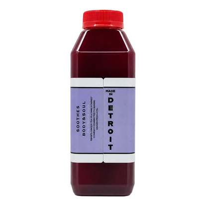 A bottle of maroon juice with a red cap and a lavender-purple label, set against a plain white background.