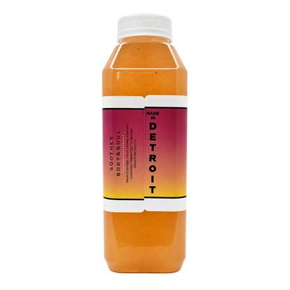 A bottle containing a drink with an orange-amber liquid, a white cap, and a pink-to-yellow gradient label on a white background.