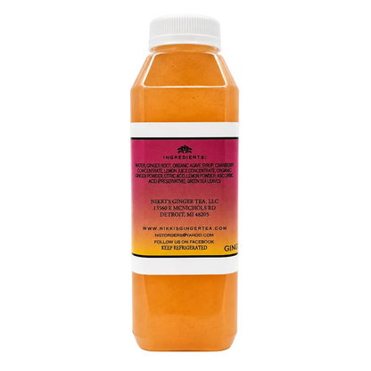 A bottle of ginger tea with orange liquid, a white cap, and a white label with red and yellow bands, photographed on a white background.