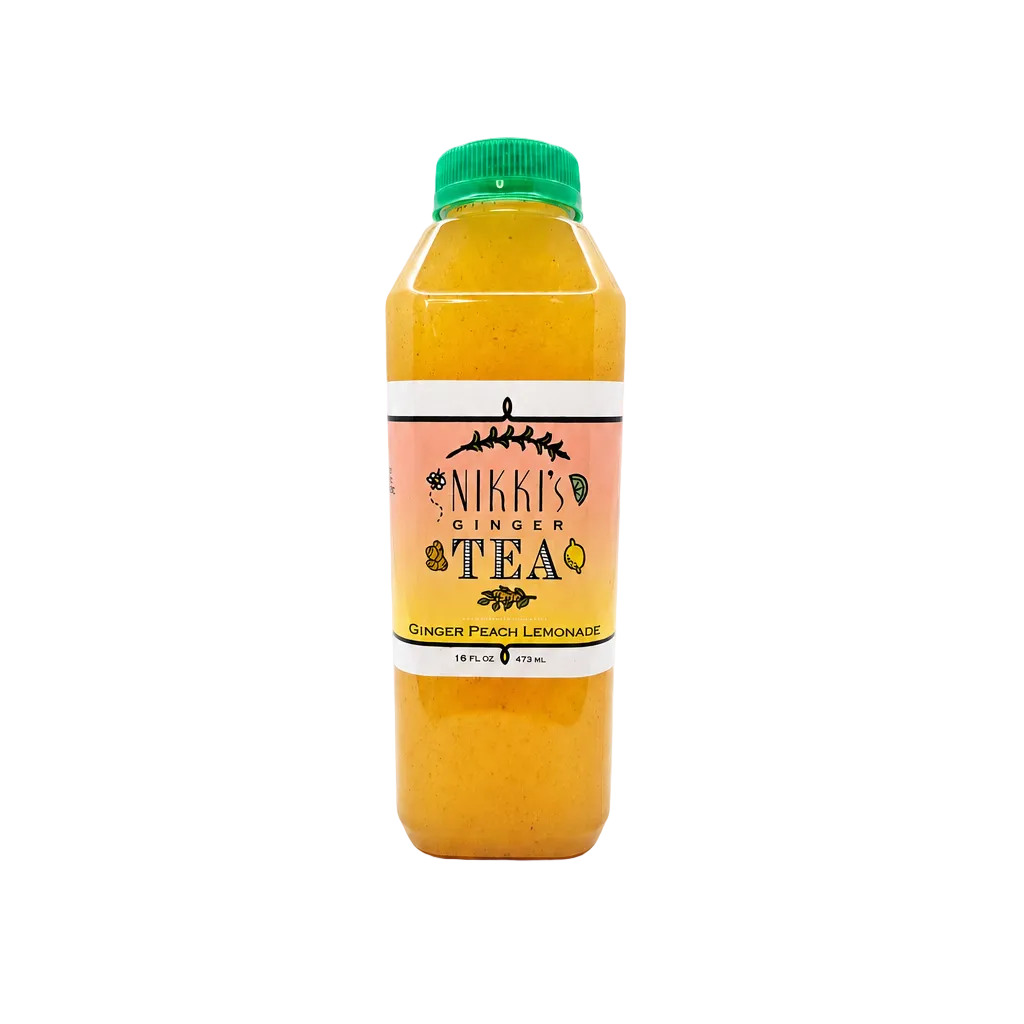 A bottle of Nikke's Ginger Tea juice with orange-yellow liquid, a green cap, and a peach and white label, centered on a light gray background.