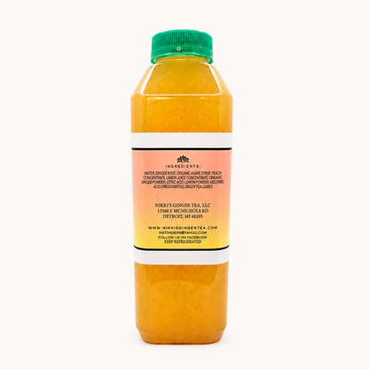 A bottle of ginger peach lemonade, showing the back of the clear plastic bottle filled with orange tea and topped with a green cap, set against a plain white background.