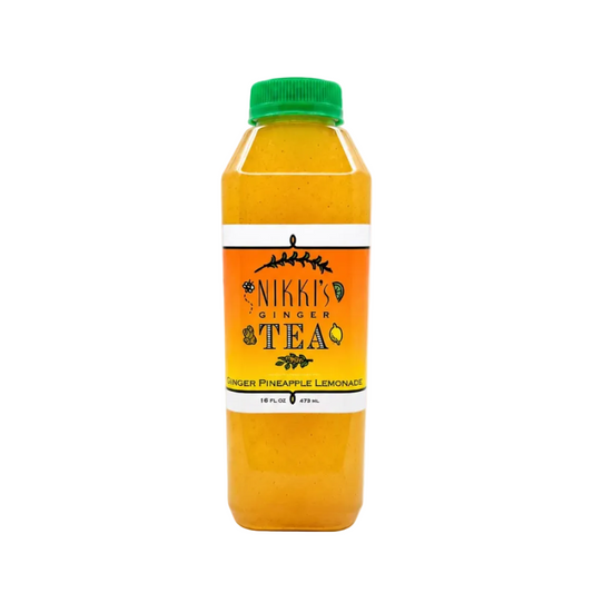 A bottle of Nikki's Ginger Tea in Pineapple Lemonade flavor, filled with a bright yellow-orange liquid, featuring a green cap and a white and orange label, set against a plain white background.